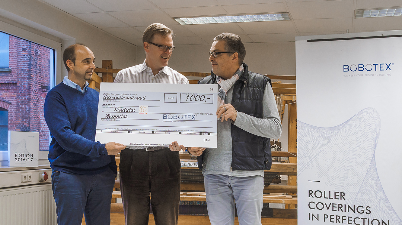 Die Geschäftsführer von Bobotex überreichen einen Spendenscheck an einen Repräsentanten von Kindertal e. V.